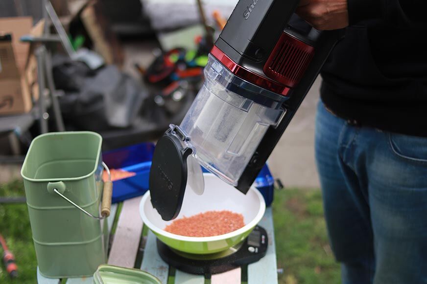 The dirt container of the Shark Anti Hair Wrap Flexology is seen being emptied.